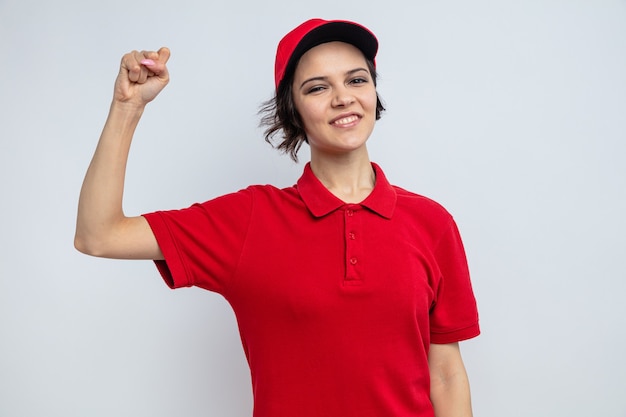 Free photo smiling young pretty delivery woman standing with raised fist