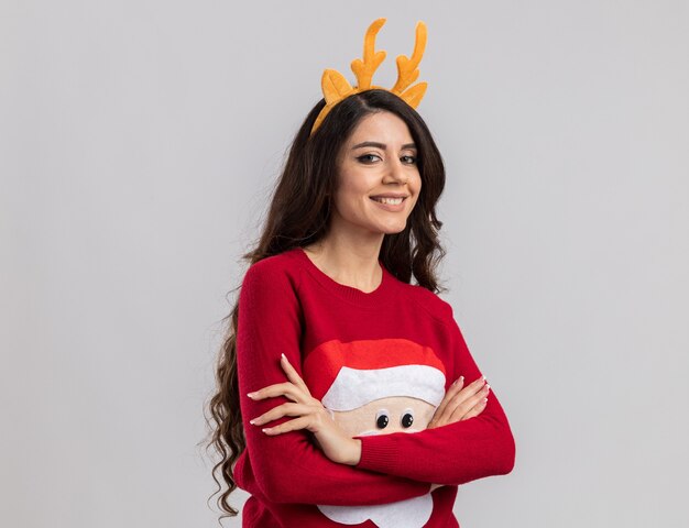 Smiling young pretty girl wearing reindeer antlers headband and santa claus sweater 