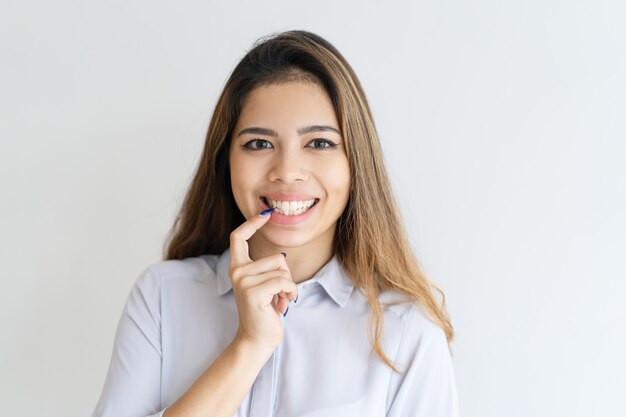 Smiling young pretty woman looking at camera and touching lip