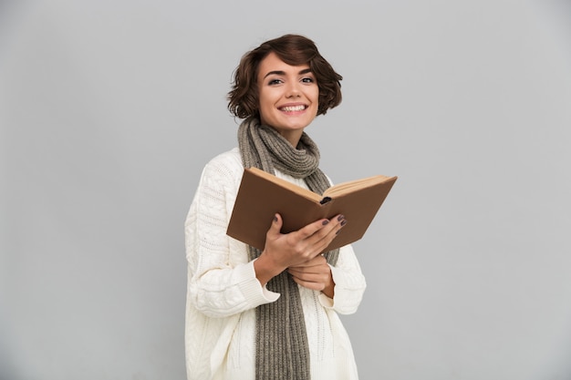 Smiling young pretty woman wearing scarf reading book.