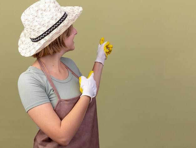 ガーデニングの帽子と手袋を身に着けている若いスラブの女性の庭師の笑顔