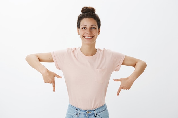 Smiling young stylish woman posing against the white wall