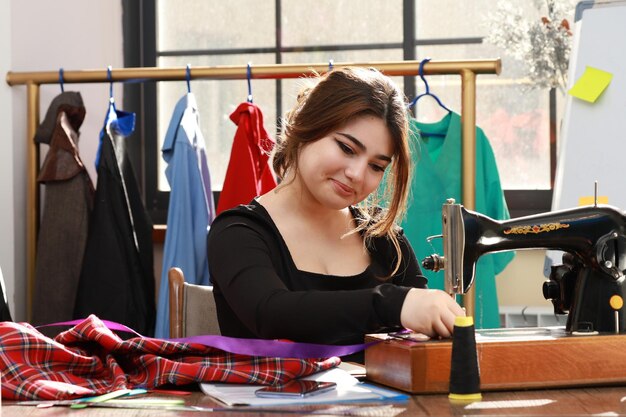 Smiling young tailor and sewing clothes