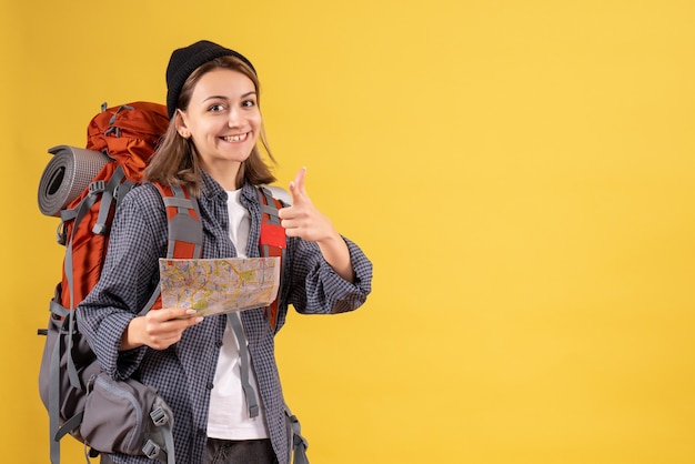 smiling young traveller with backpack holding map pointing at camera