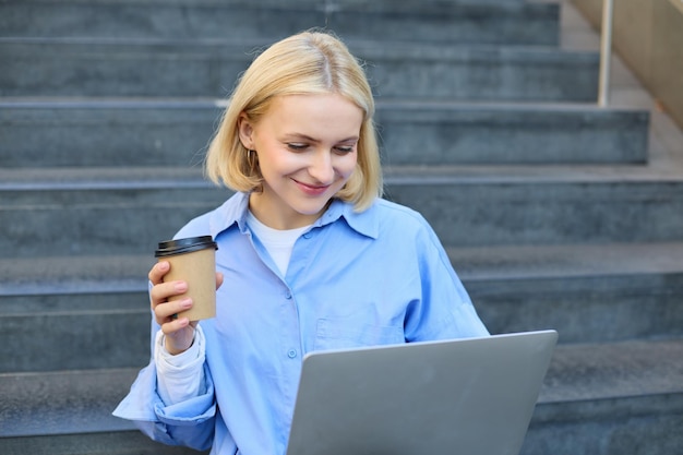 smiling-young-urban-woman-student-working-laptop-sitting-outdoors-stairs-drinking-coffee_1258-208826.jpg