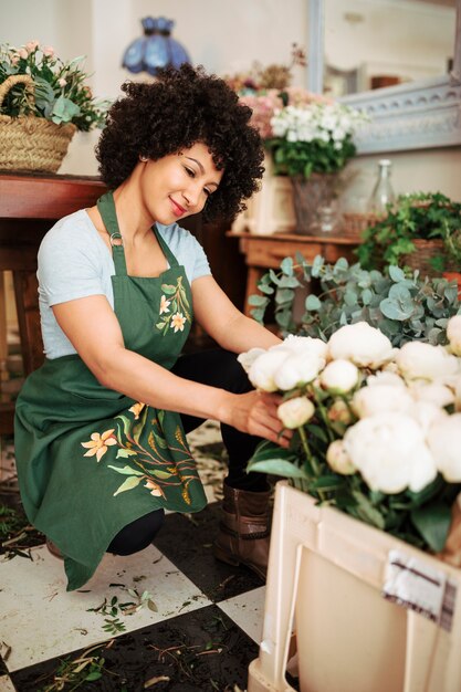 Smiling young woman arranging white peony flowers