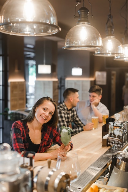 Smiling young woman at bar counter with drinks