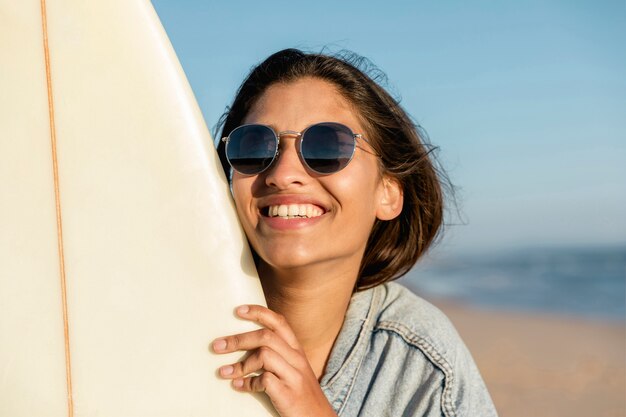 サーフボードとビーチで笑顔の若い女性