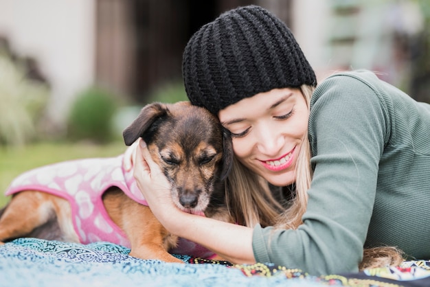 彼女のフレンドリーな犬を抱擁する笑顔の若い女性