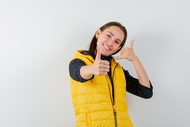 Smiling young woman doing a call me hand sign and showing a good hand sign on white background