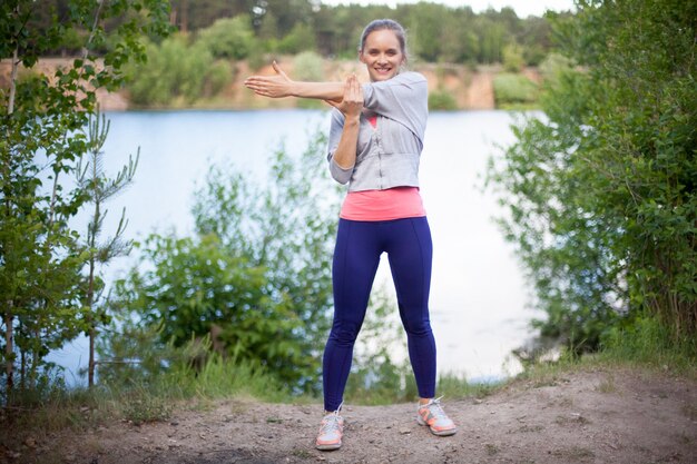 Smiling young woman doing exercises outdoors