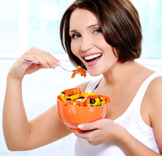 笑顔の若い女性がサラダを食べる