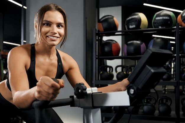 Smiling young woman engaged on exercise bike