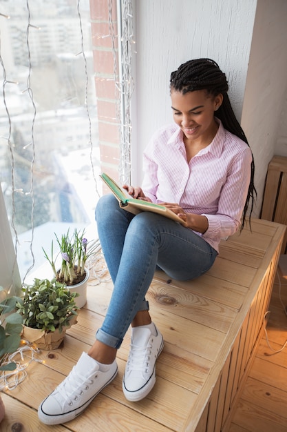 Free photo smiling young woman enjoying favorite book