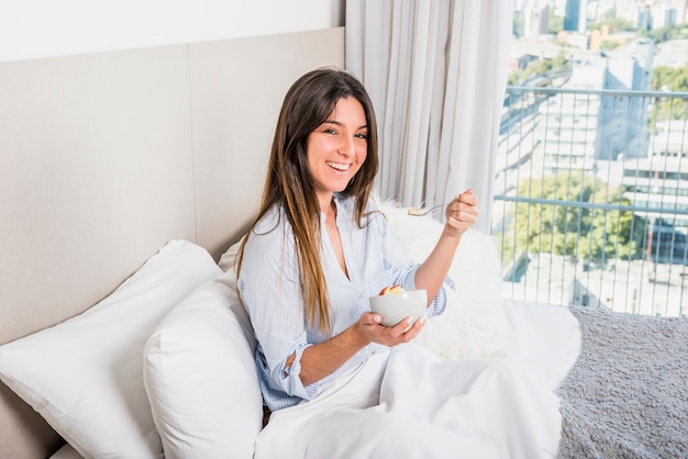 Smiling young woman enjoying the healthy fruit breakfast