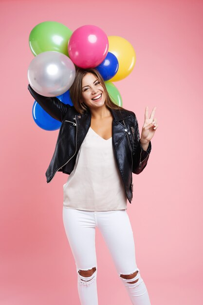 Smiling young woman in fancy outfit showing peace sign