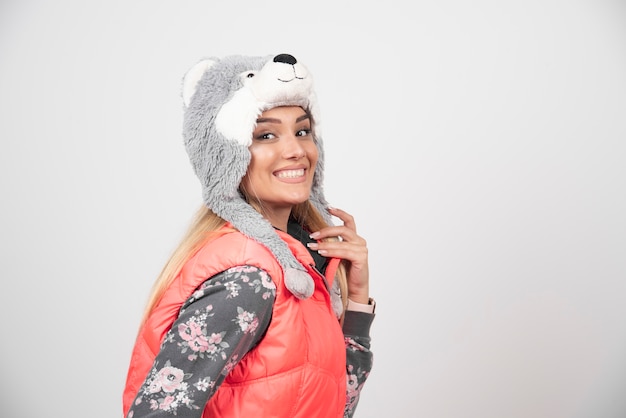 Free photo smiling young woman in funny hat on a white wall.