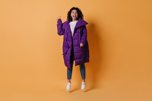 Smiling young woman gesturing on yellow wall