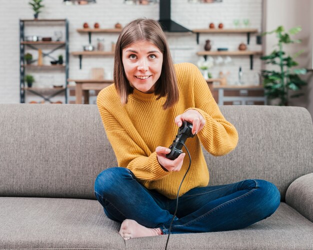 Smiling young woman having fun playing video console game at home