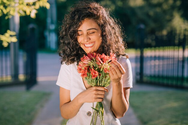 花の花束を手で押し笑顔の若い女性