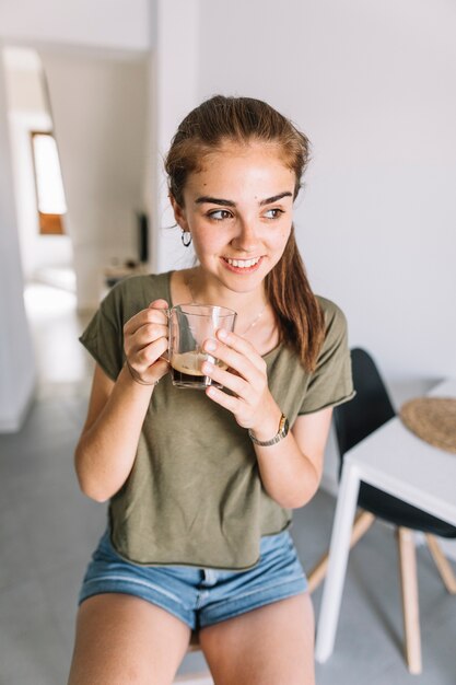 Smiling young woman holding glass of coffee