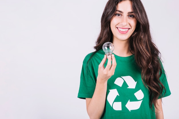 Smiling young woman holding light bulb on white background