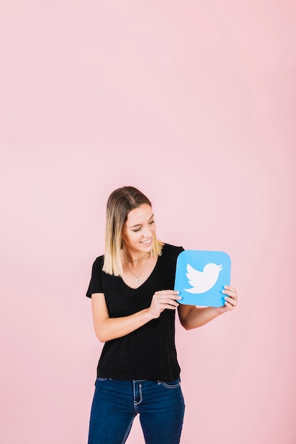 Smiling young woman holding twitter icon