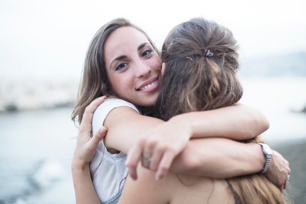 그녀의 여자 친구를 포옹 웃는 젊은 여자