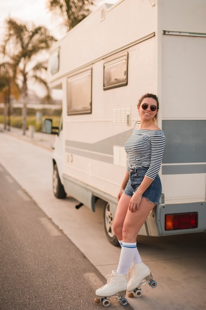 Free photo smiling young woman leaning on caravan