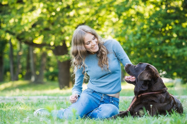 公園で彼女の犬を見て笑顔の若い女性