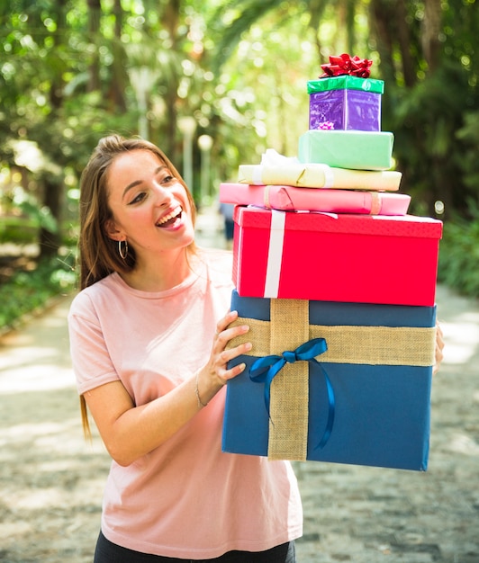 Smiling young woman looking at stack of gifts