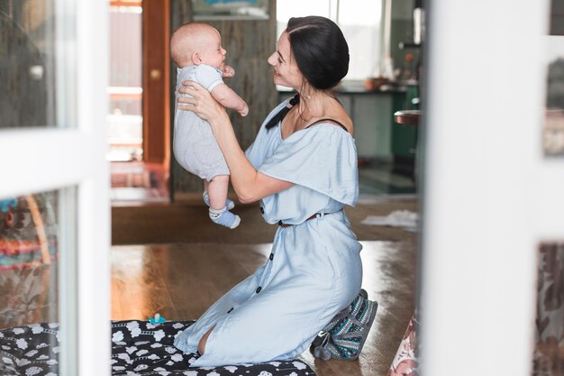 Smiling young woman playing with her baby at home