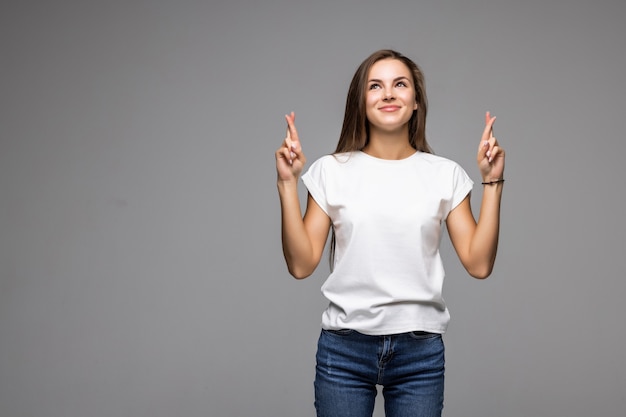 Free photo smiling young woman pointing finger up isolated on gray