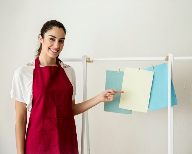 Smiling young woman pointing at hanging handmade papers