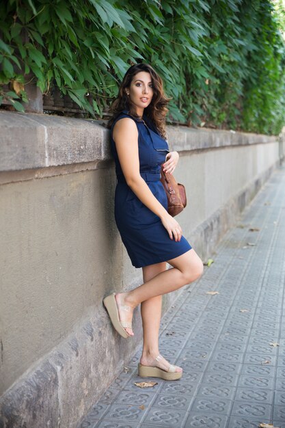 Smiling young woman posing at concrete fence