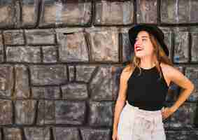 Free photo smiling young woman posing in front of wall