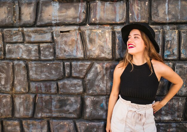 Smiling young woman posing in front of wall