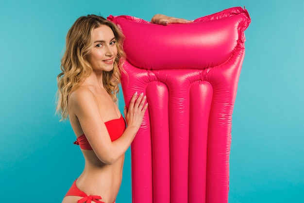 Free photo smiling young woman posing with inflatable mattress