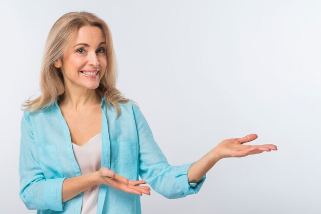 Smiling young woman presenting against white background