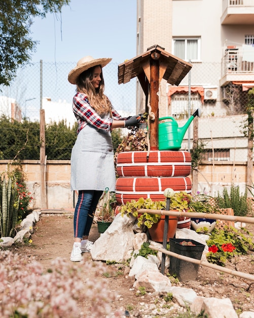 Smiling young woman pruning the plants on handmade well