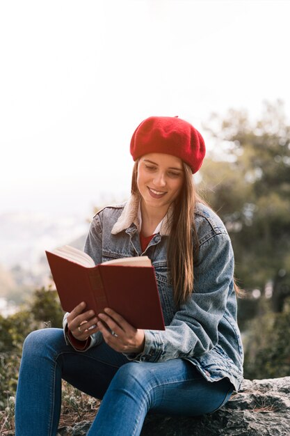 屋外で本を読んで笑顔の若い女性