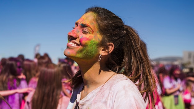 Smiling young woman's face painted with holi color