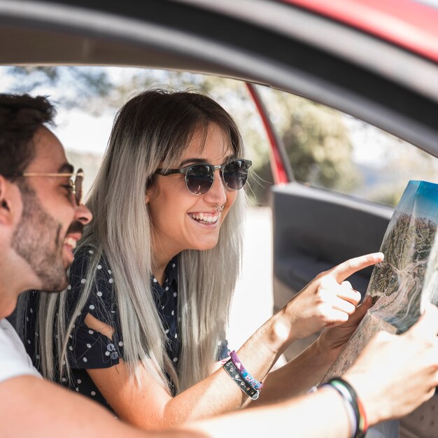 Smiling young woman showing directions on map to her boyfriend