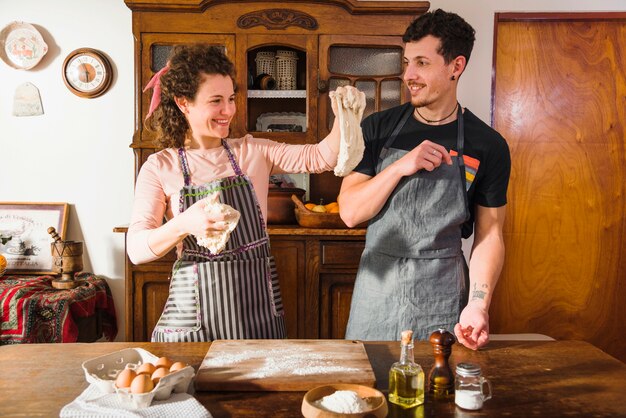 Smiling young woman showing kneaded dough to her husband