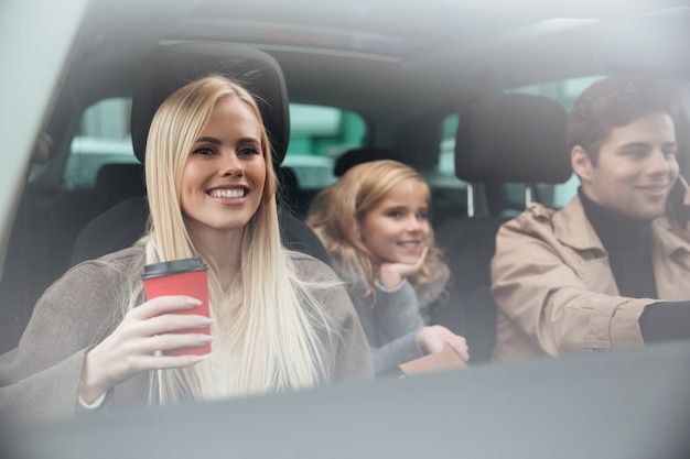 Smiling young woman sitting in car with family