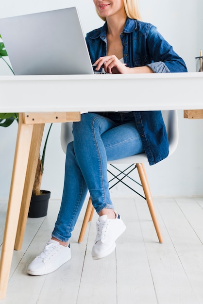 Smiling young woman sitting in chair near laptop