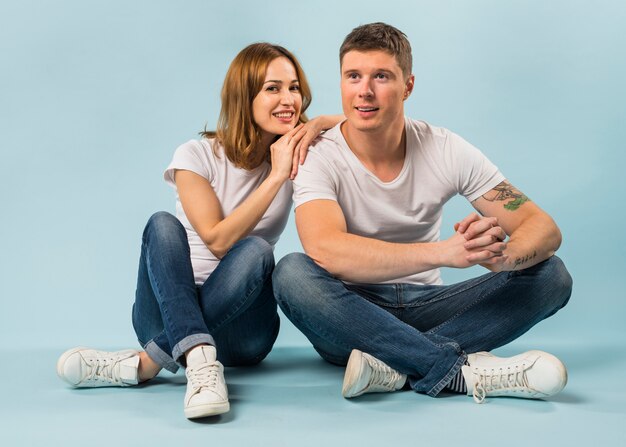 Smiling young woman sitting her boyfriend against blue background