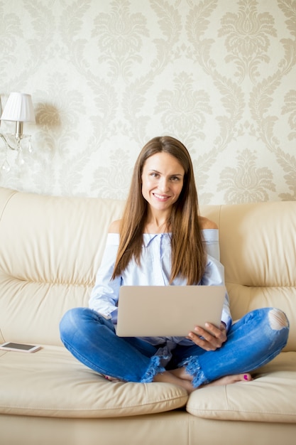Smiling young woman sitting on sofa with touchpad