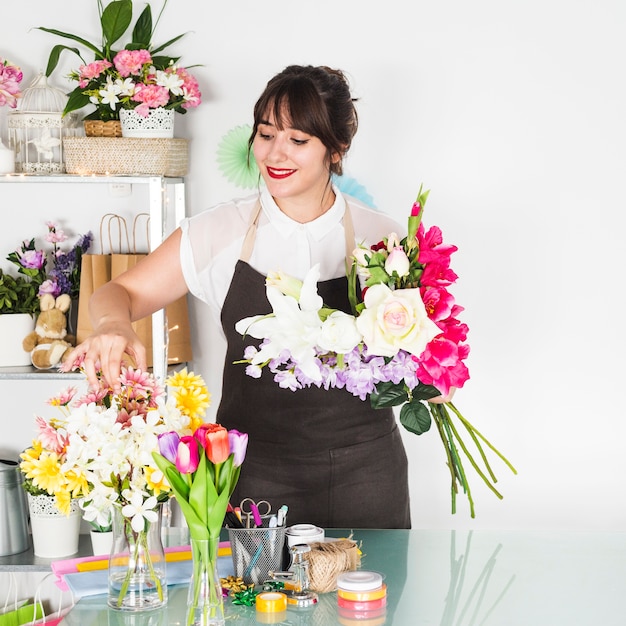 花屋で花を並べ替える笑顔の若い女性