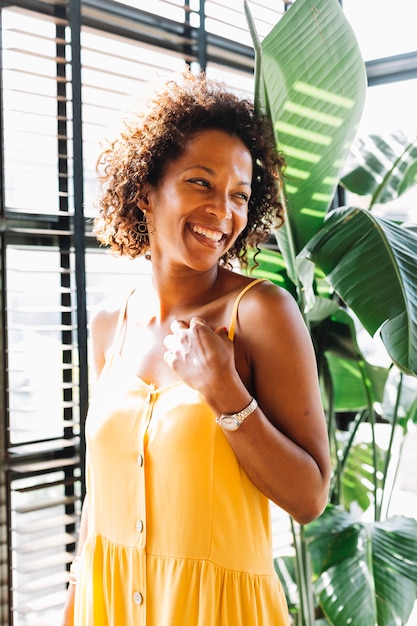 Foto gratuita giovane donna sorridente che sta vicino alla finestra al sole